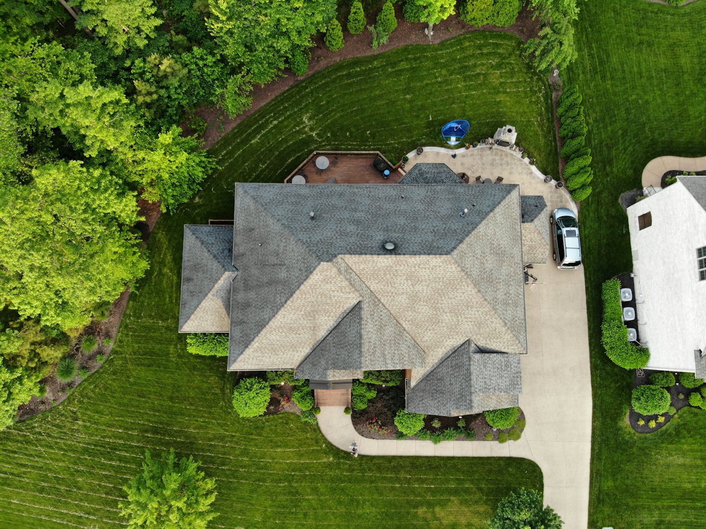 Aerial view of a large house with grey shingle roof and green lawns.